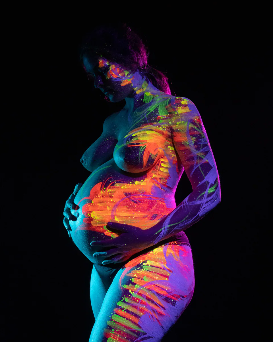 Babybauch mit leuchtendem Bodypainting im Schwarzlicht