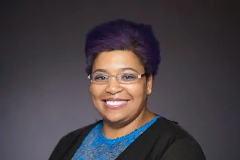 Laughing woman with short violet hair, glasses and a blue patterned top