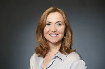 Smiling woman with shoulder-length reddish hair and a light grey blouse