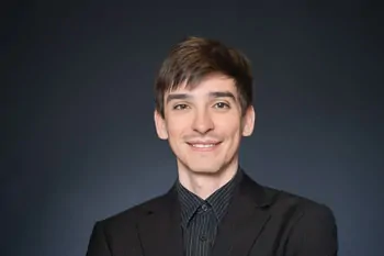 Smiling man with dark hair, a black jacket and a dark shirt