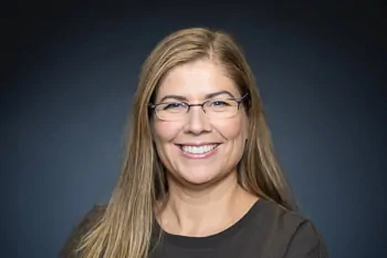 Smiling woman with long blonde hair, glasses and a black top