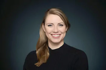 Smiling woman with brown hair tied to one side and a black top