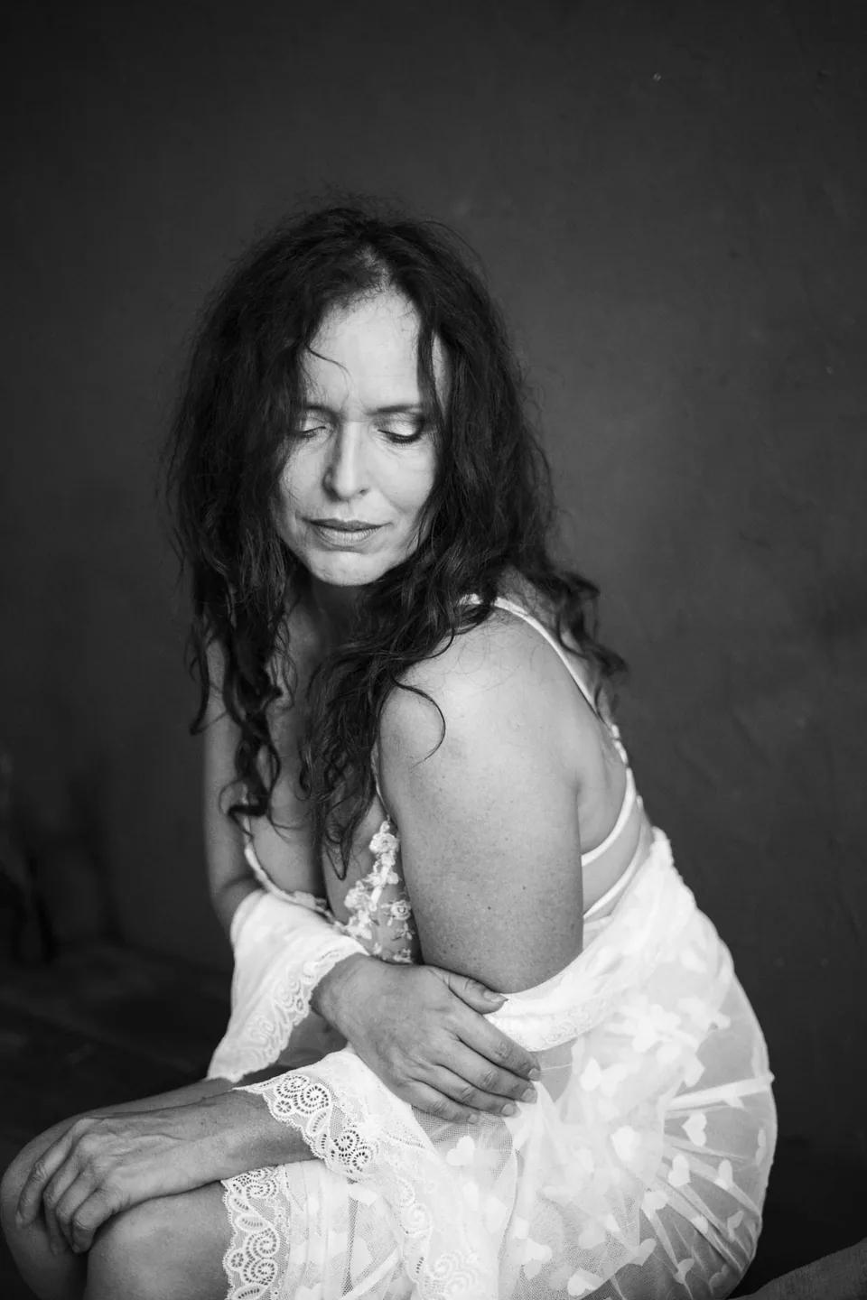 A black-and-white portrait of a woman in pale lace with her eyes closed