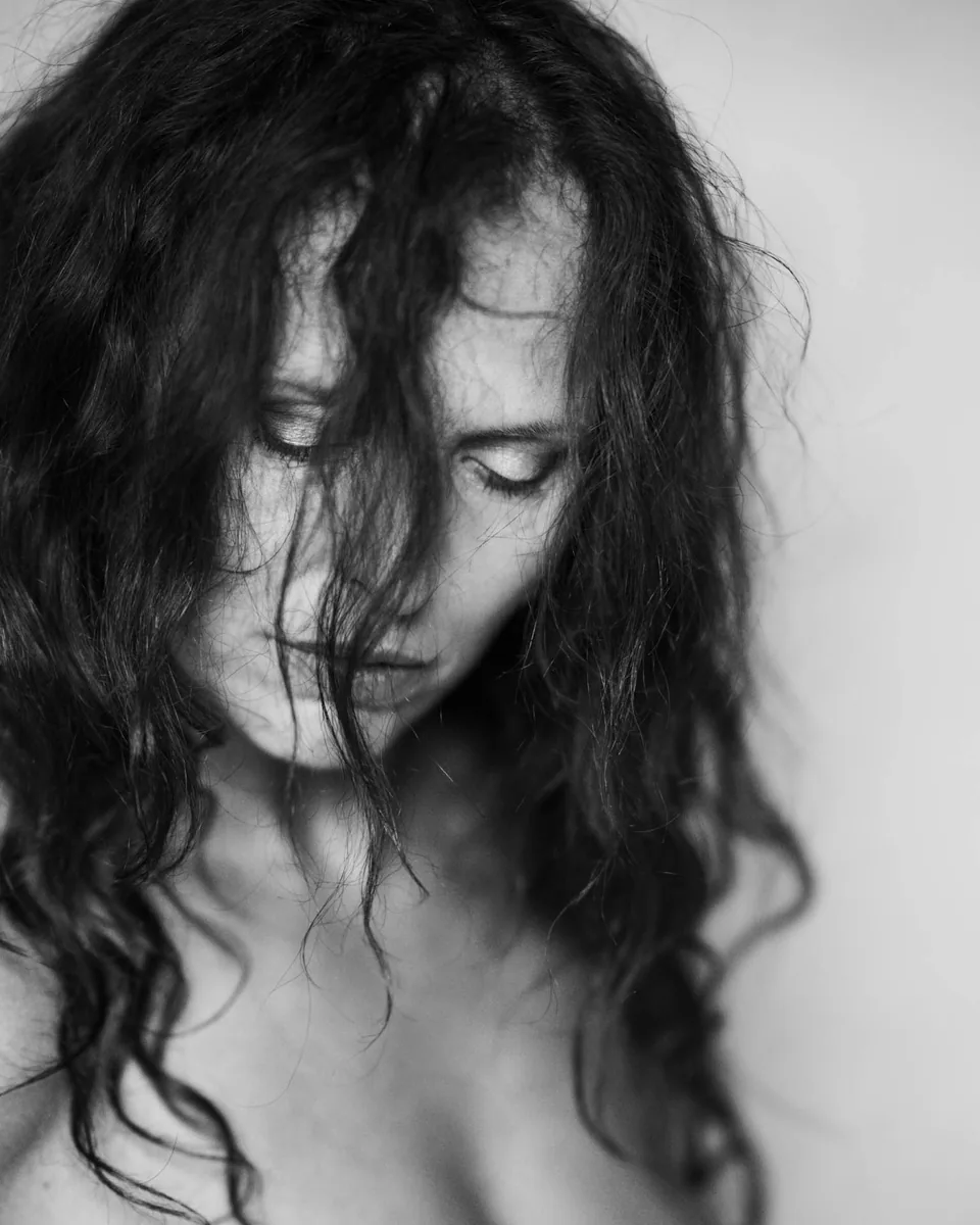 Black-and-white close-up portrait of a woman with long hair against a light background