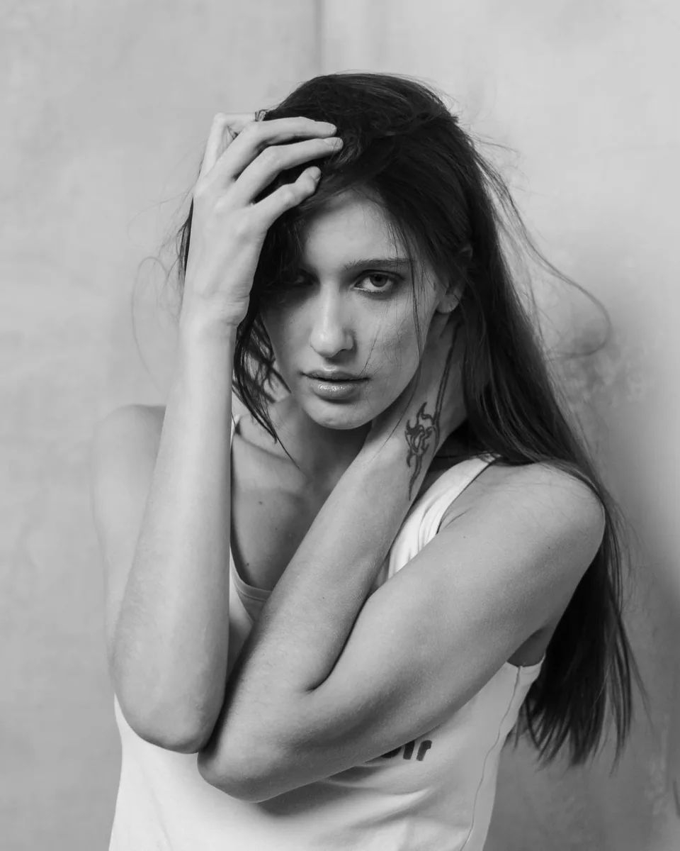 Black-and-white portrait of a woman with long hair and tattoos