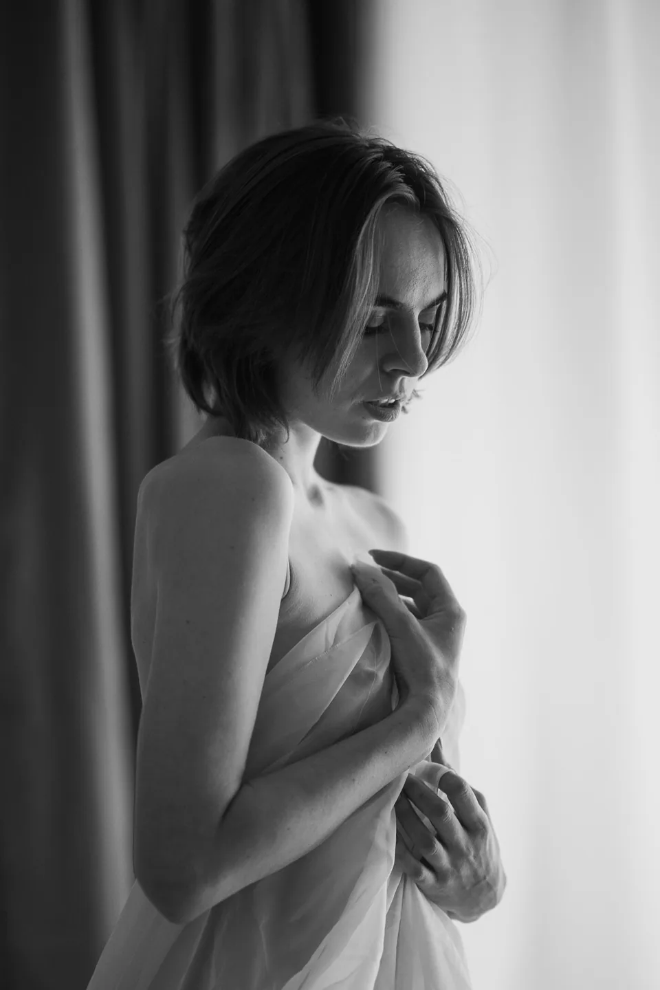 Schwarz-Weiß-Portrait einer Frau mit einem Tuch am Fenster