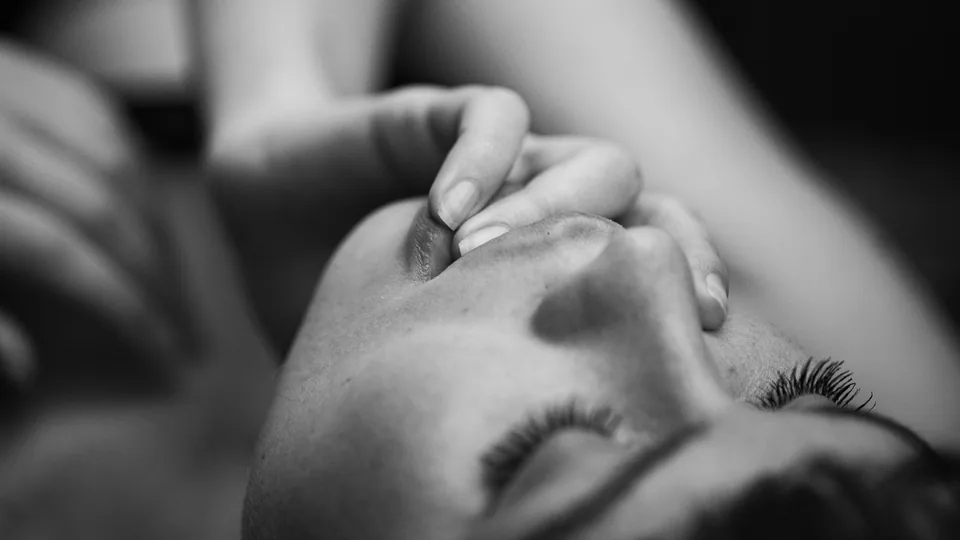 A black-and-white close-up of a reclining woman with her hand resting on her face