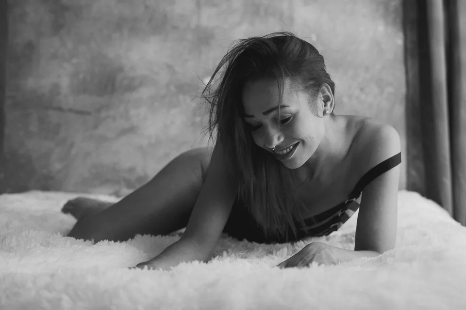 Laughing woman during a relaxed boudoir shoot on the bed