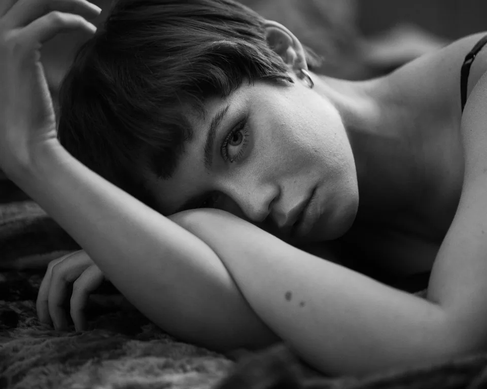 A natural boudoir portrait of a reclining woman with a direct gaze