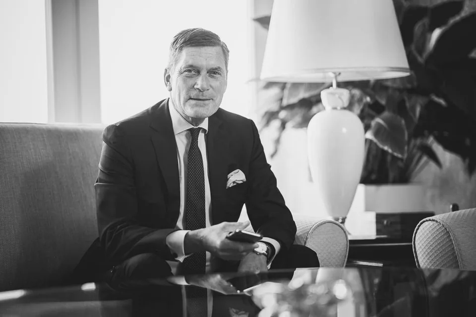 Schwarz-Weiß-Portrait eines Mannes im Anzug mit einem Telefon in der Hand