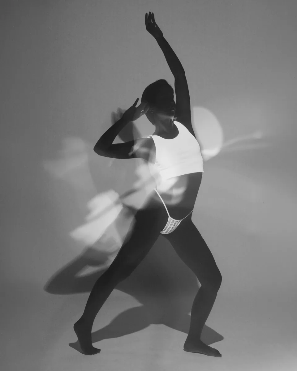 Schwarz-Weiß-Porträt einer Person mit erhobenem Arm, Lichtreflexen und Schatten
