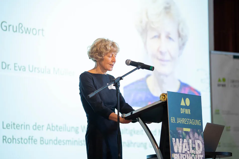 Woman speaks at a lectern in front of a projection screen