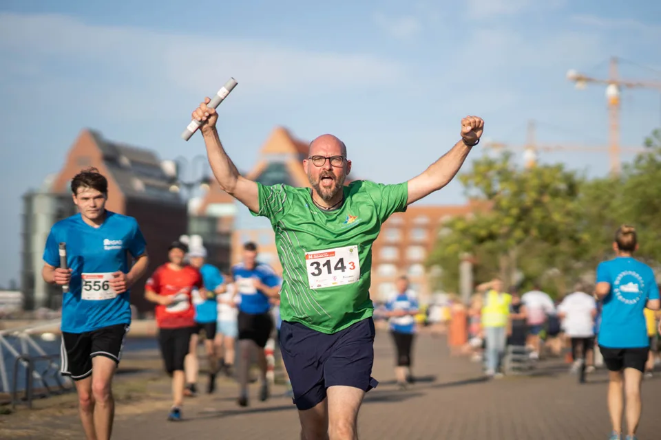 Relay runner with raised baton at Rostock city harbour