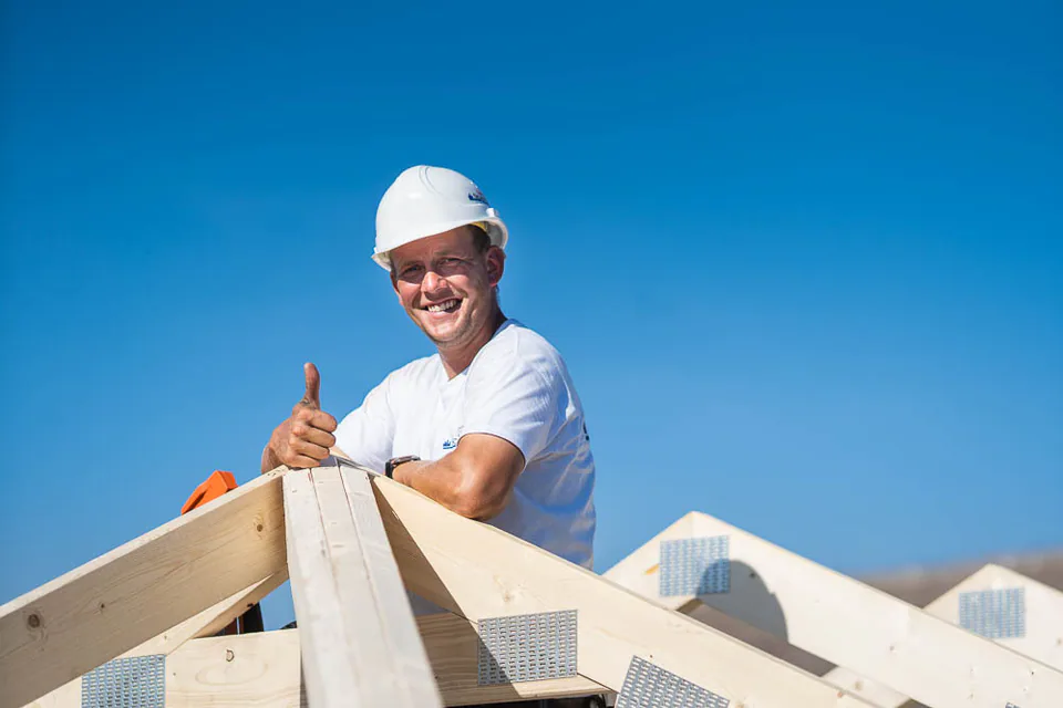 Mann mit weißem Helm steht auf einem Dachstuhl