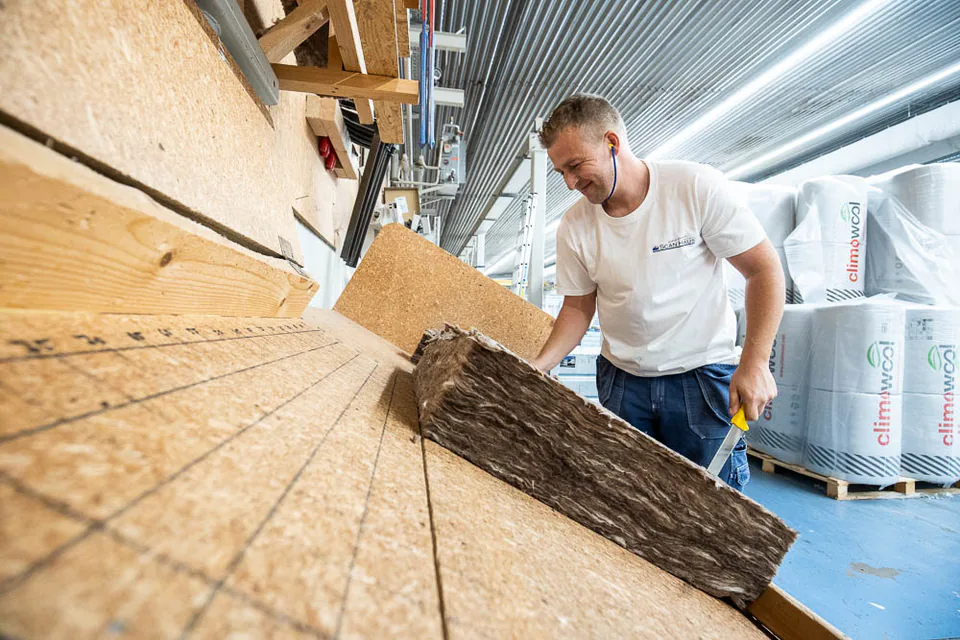 Mann bearbeitet Dämmstoff in einer Produktionshalle