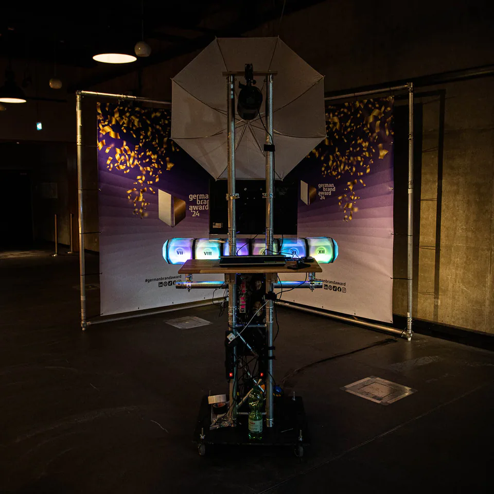A Photo Booth setup with a camera, umbrella light and illuminated elements