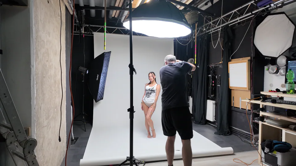 Fotograf bei einem Shooting mit Studiolicht vor weißem Hintergrund