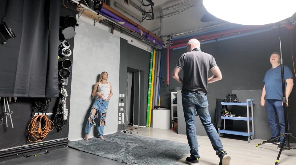 Fotograf und Person im Fotostudio vor neutralem Hintergrund.