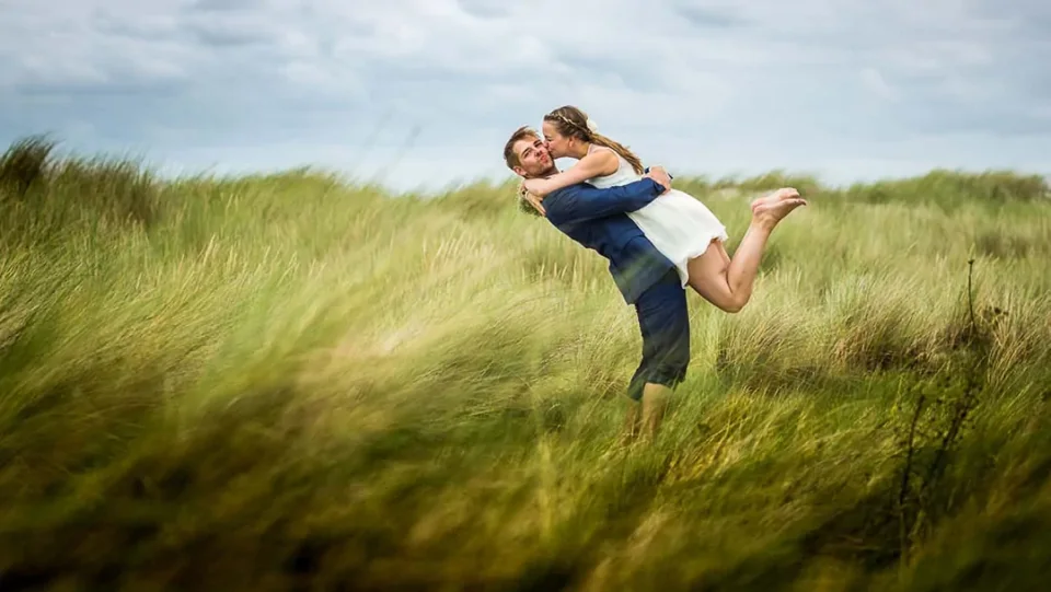 A wedding couple playing around in the dunes at Dierhagen in strong wind