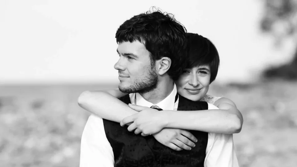A close-up black-and-white portrait of a wedding couple on the beach