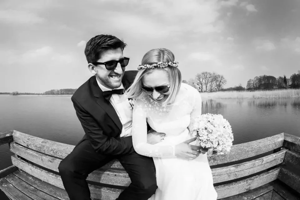 Black-and-white wedding photo of a bride and groom on a pier