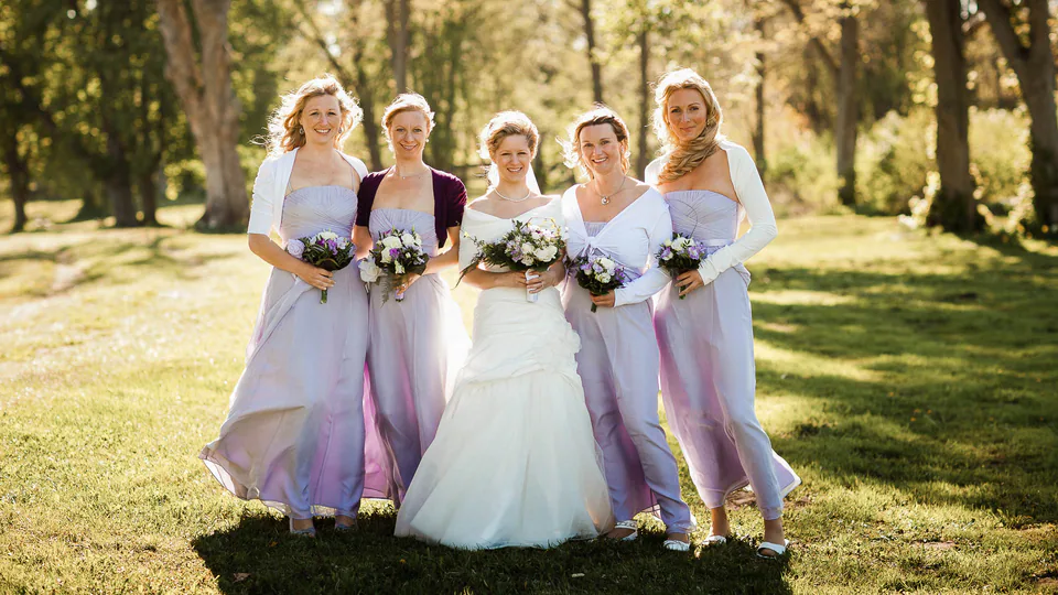 Braut mit vier Frauen und Blumensträußen auf einer Wiese