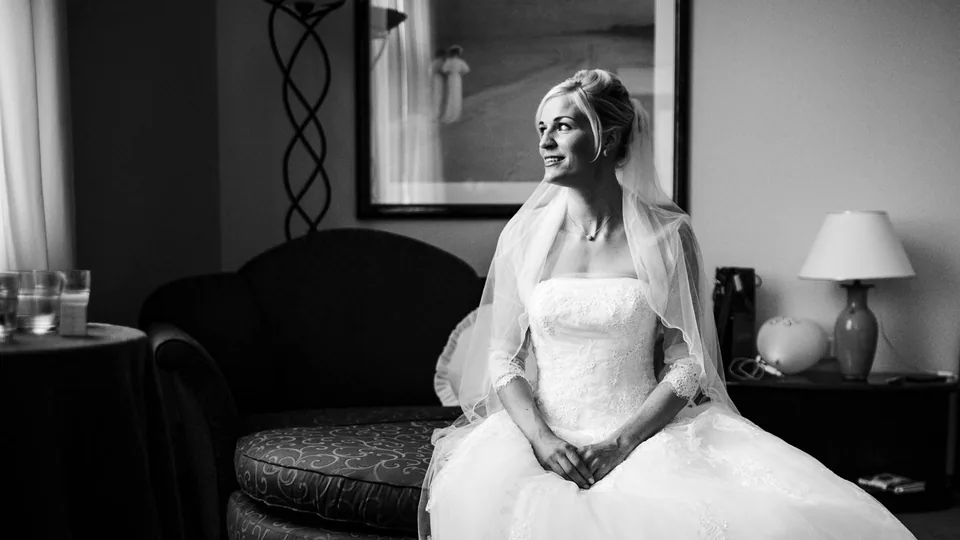 Braut sitzt im Hochzeitskleid auf einem Sofa