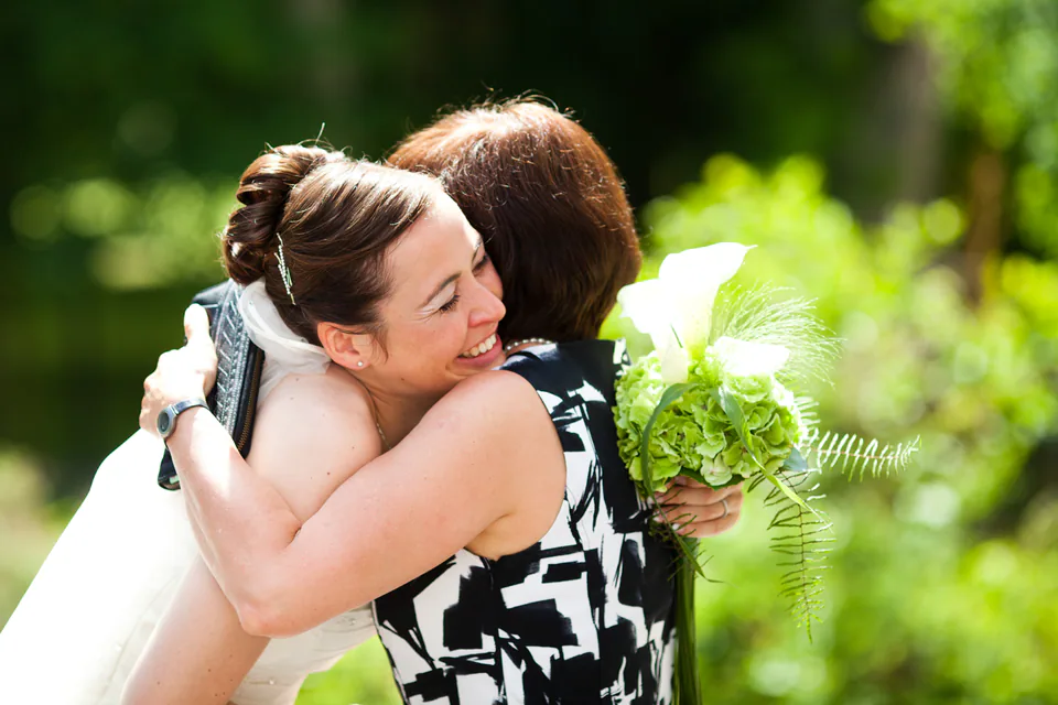 Braut umarmt eine Frau mit Blumenstrauß