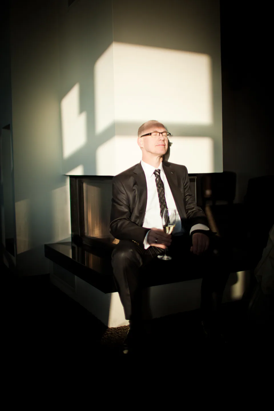 Mann im Anzug sitzt mit einem Glas im Sonnenlicht