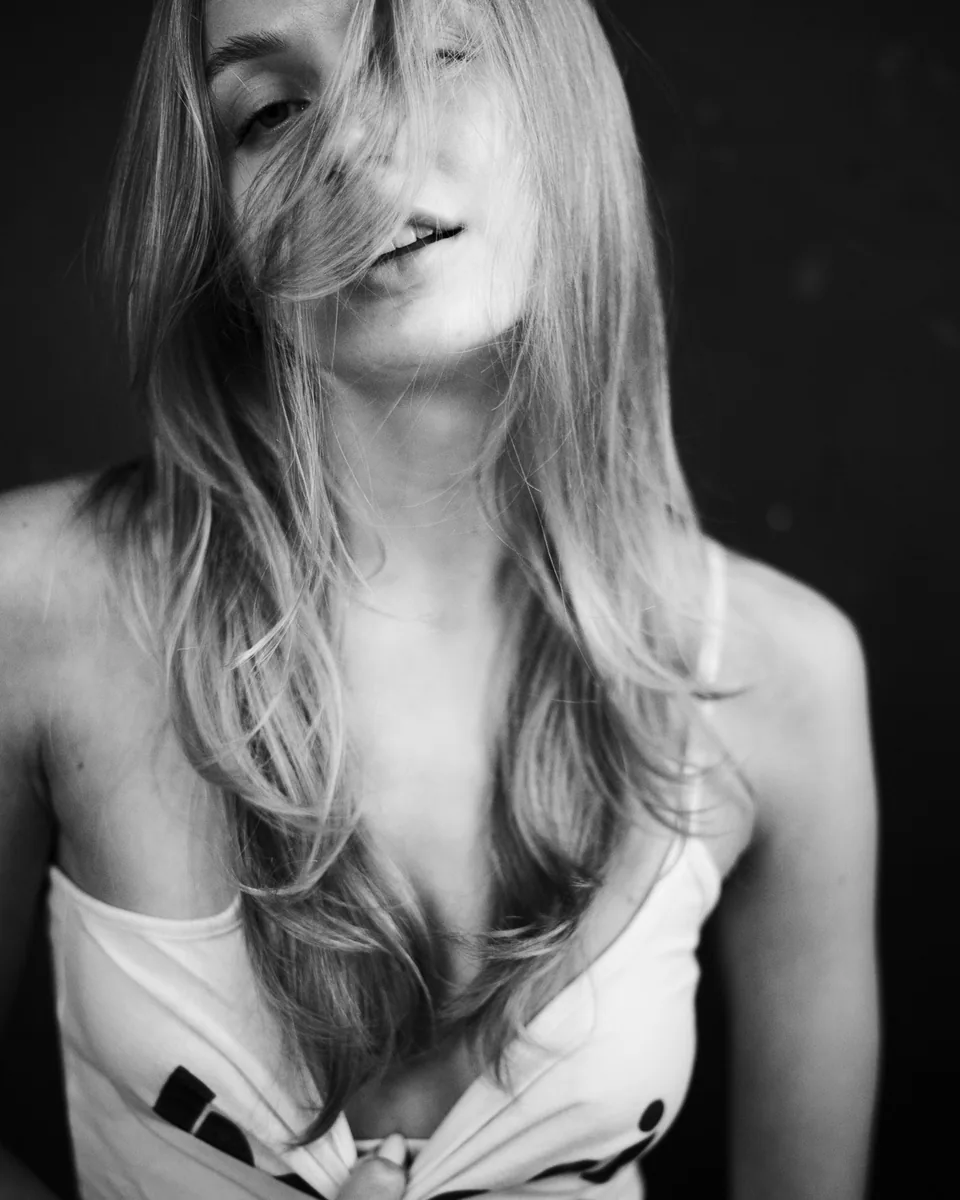 Nahes Schwarz-Weiß-Portrait einer blonden Frau mit Haaren vor dem Gesicht
