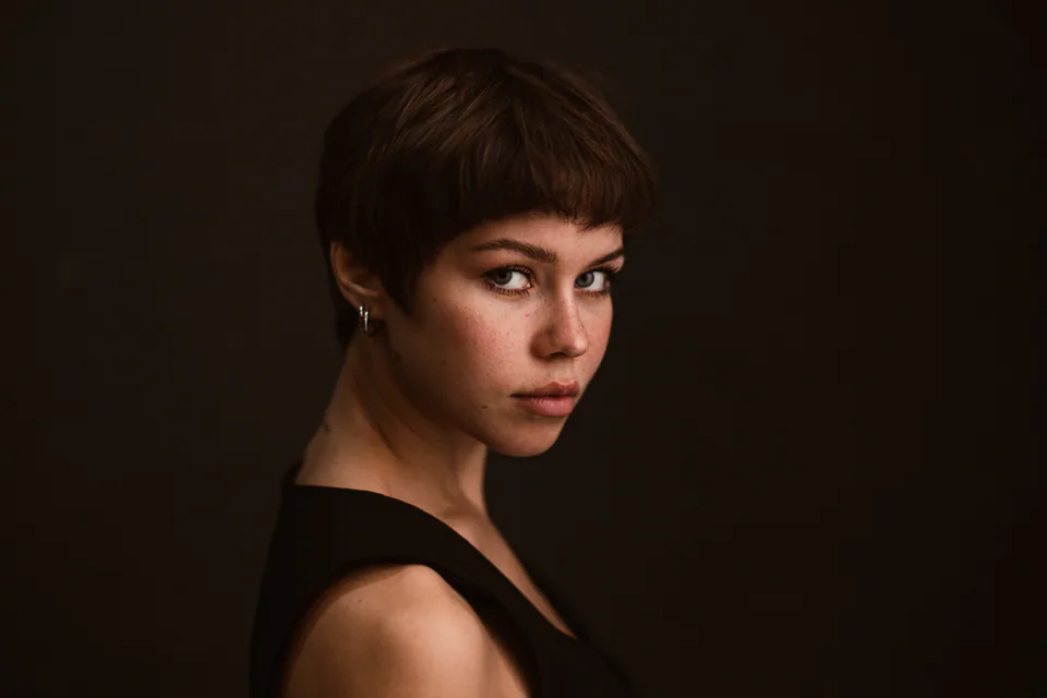 Portrait einer Frau mit kurzen dunklen Haaren vor dunklem Studiohintergrund