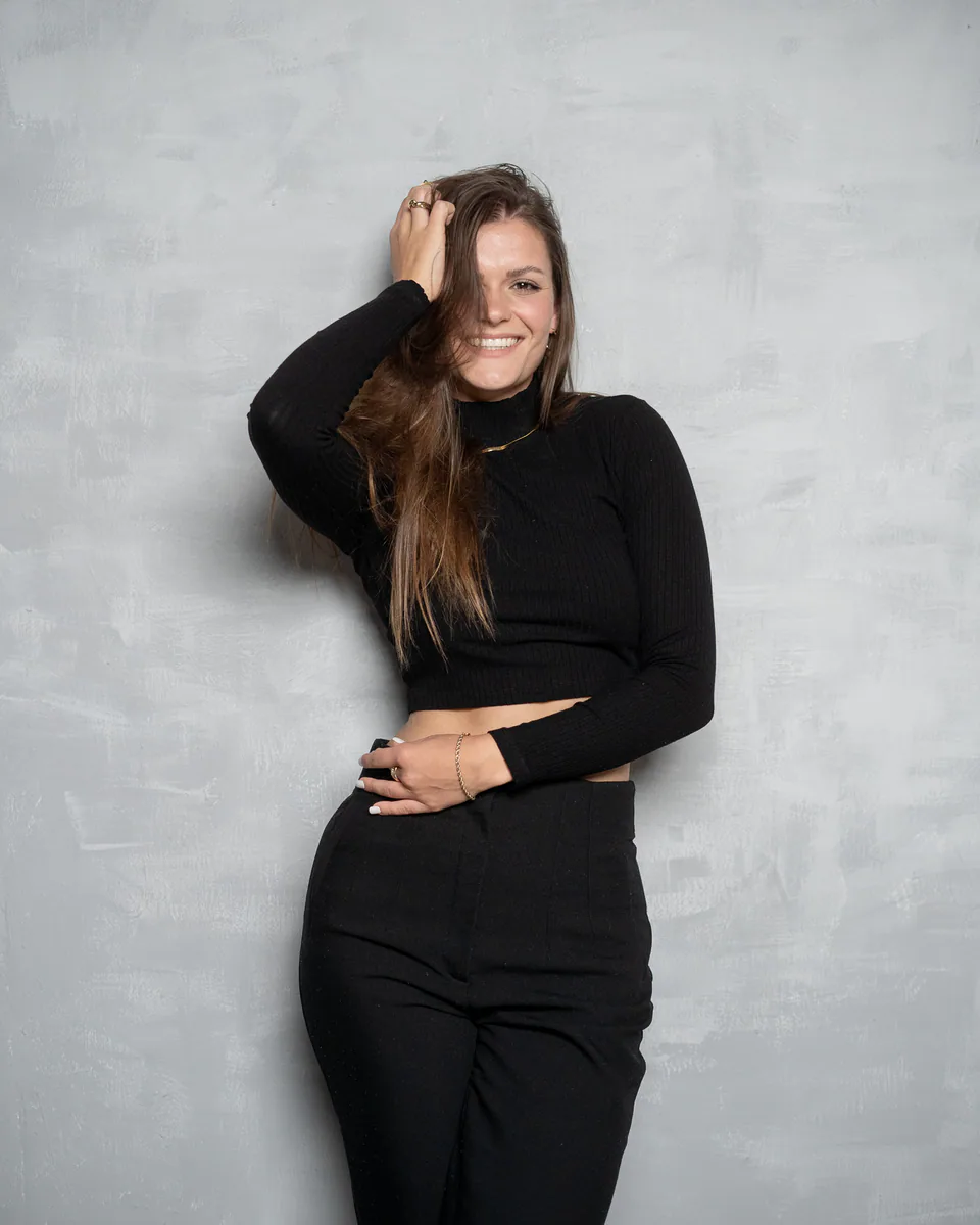Lachende Frau in schwarzem Outfit vor grauem Hintergrund bei einem Portraitshooting in Rostock