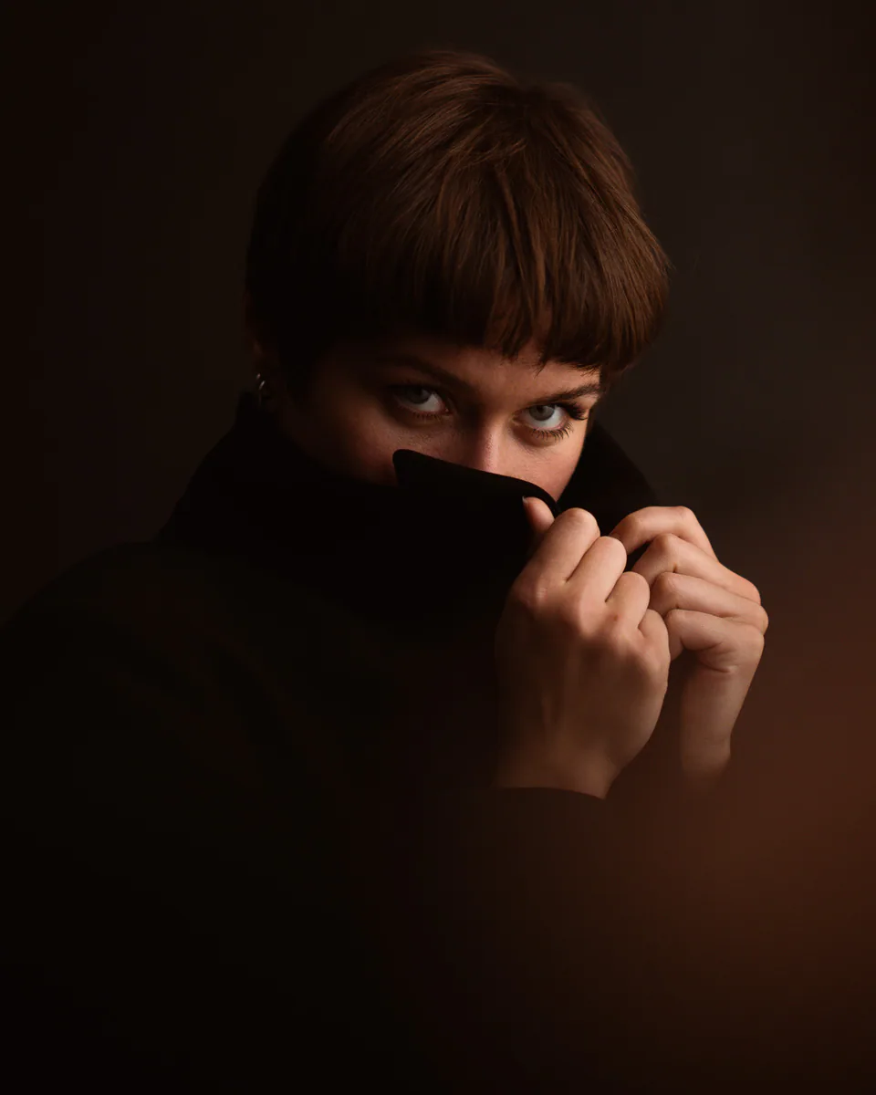 Portrait einer Frau mit hochgezogenem schwarzen Kragen und direktem Blick