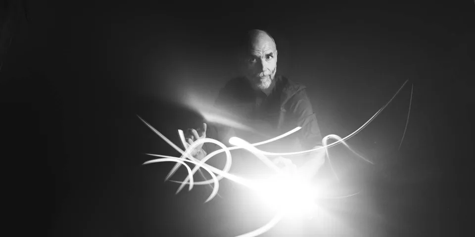 Schwarz-Weiß-Portrait eines Mannes mit hellen Lichtspuren vor dunklem Hintergrund