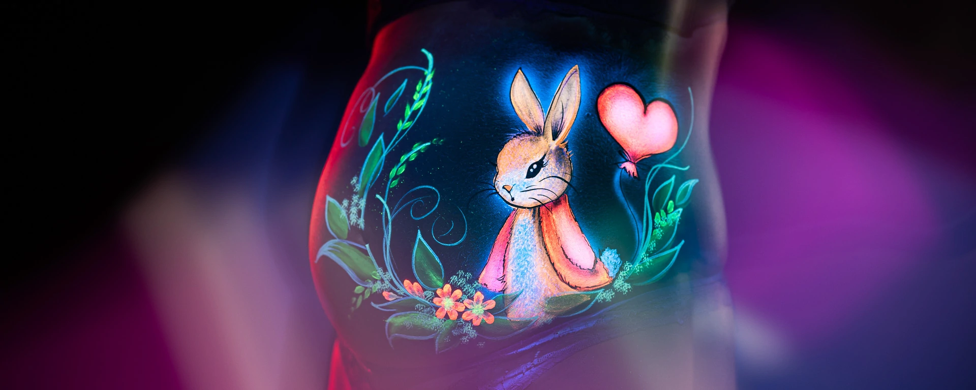 Kreatives Babybauch Bodypainting mit Schwarzlicht und farbigen Elementen