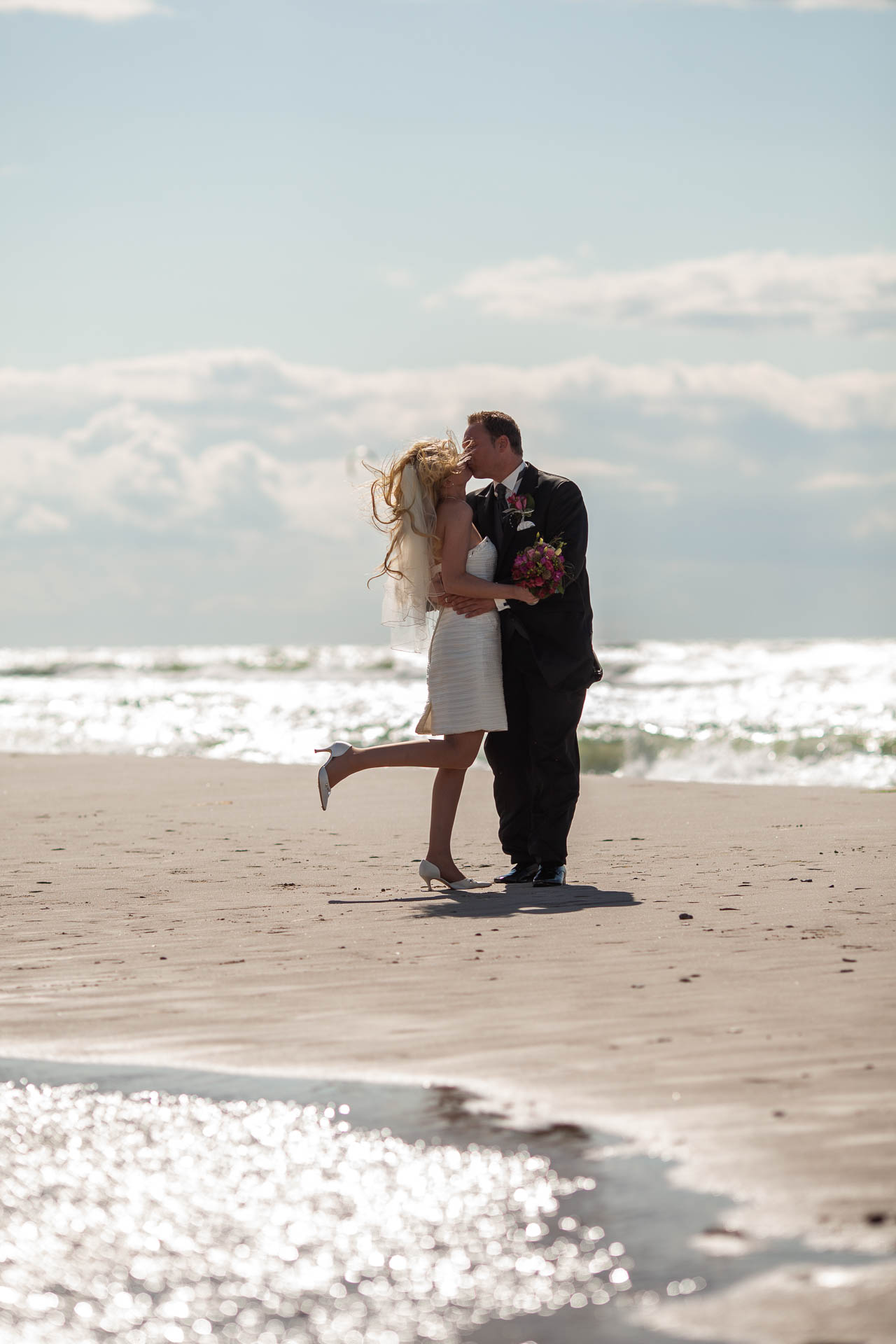 Hochzeitsfotograf Dierhagen – Brautpaar Kuss am Ostseestrand Brautpaar küsst sich am Strand von Dierhagen an der Ostsee bei windigem Wetter