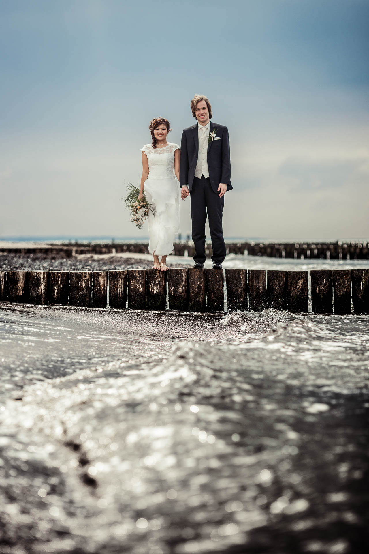 Hochzeitsfotograf Graal-Müritz – Brautpaar auf Buhne an der Ostsee Brautpaar steht auf Buhne in Graal-Müritz. Wellen der Ostsee im Vordergrund